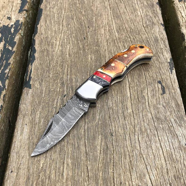 Damascus folding pocket knife by cskforged with burnt camel bone handle, showcasing handcrafted design and sharp blade.