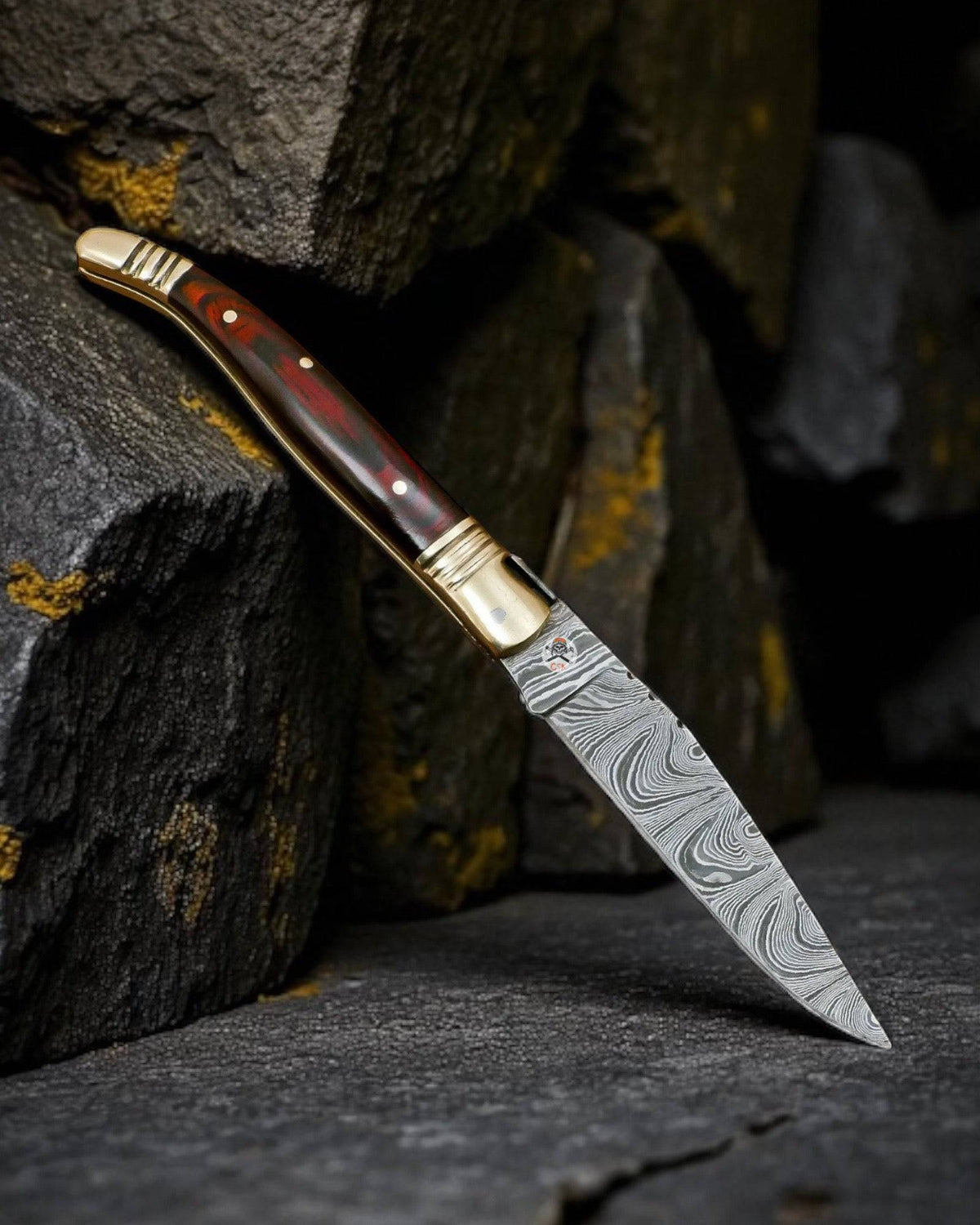 Damascus steel folding pocket knife by cskforged with handcrafted brass accents and exotic wood handle, open blade visible.