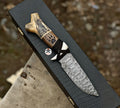 Hand-forged Damascus hunting knife with carved antler handle by cskforged, featuring a detailed blade and polished wood accents.