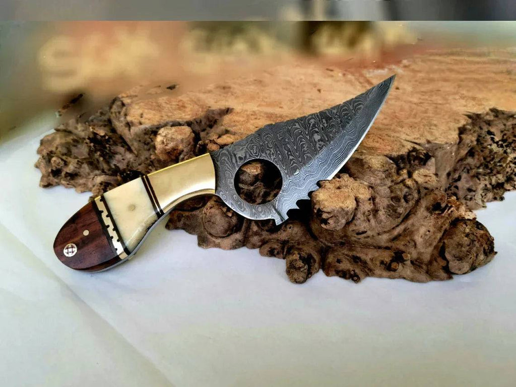 Damascus steel EDC skinning knife with bone-rose wood handle, brass bolster, and serrated edge by cskforged.