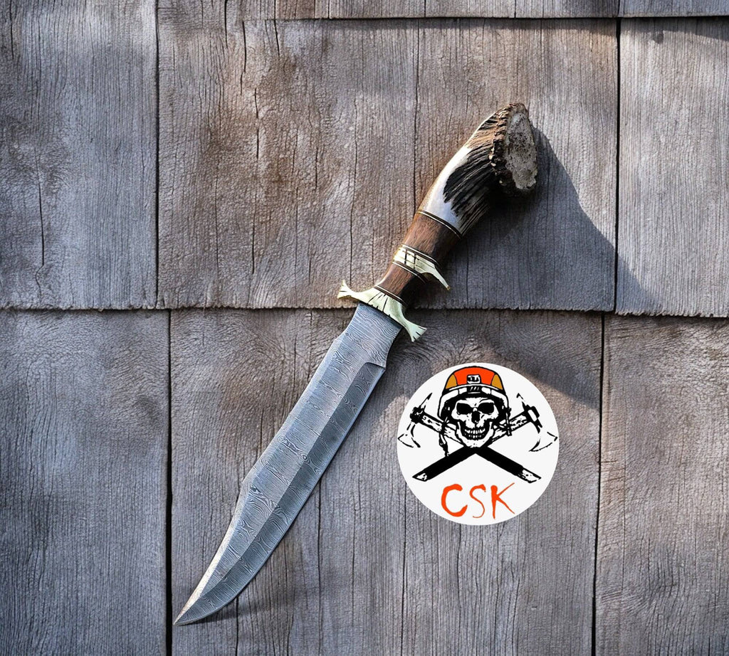 Cskforged 15-inch Damascus steel camping knife with rosewood handle, stag accents, brass guard, and leather sheath.
