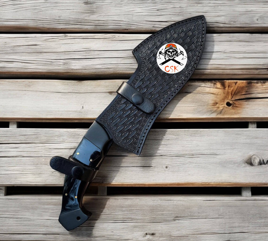 Black-coated hand-forged steel hunting knife with horn handle and custom leather sheath by cskforged.