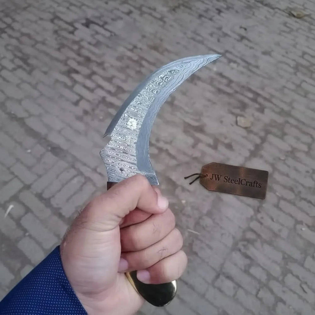 Damascus steel JW SteelCrafts karambit knife with curved blade and textured handle, displayed on a neutral background.