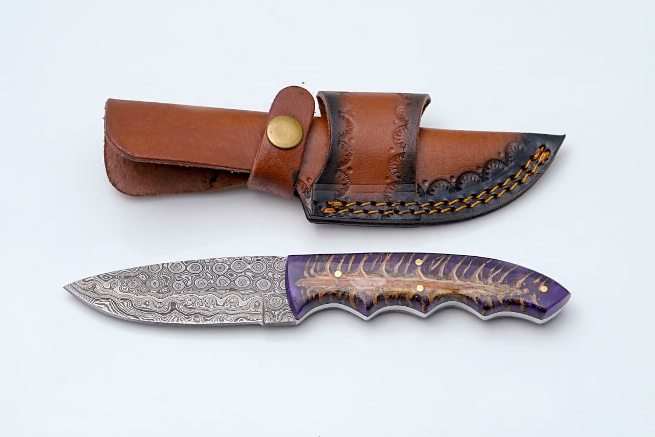 Handmade Damascus steel knife with purple pine cone handle and leather sheath, crafted by Titan International K.
