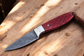 Custom handmade Damascus steel Buckaroo waist knife displayed with a leather sheath, showcasing intricate blade pattern and craftsmanship.