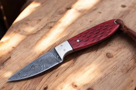 Custom handmade Damascus steel Buckaroo waist knife displayed with a leather sheath, showcasing intricate blade pattern and craftsmanship.