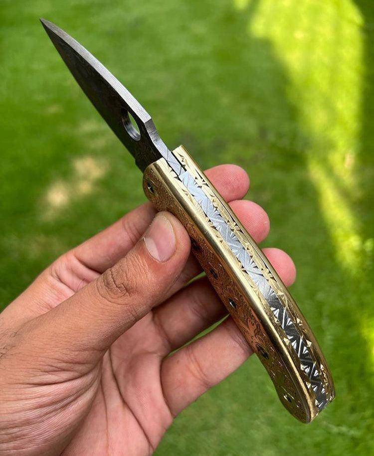 Damascus steel folding pocket knife with engraved brass handle by cskforged, showcasing a sleek 8-inch custom knife design.