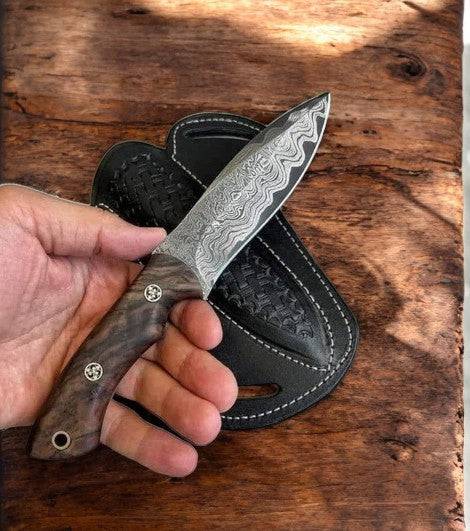 Handmade cowboy knife with walnut handle and leather sheath, crafted by Damascus Knife Store, displayed on a plain background.