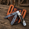 Cowboy folding trapper knife with Damascus double blades and stag handle by CSK Forged, showcasing intricate blade pattern and wood grip.