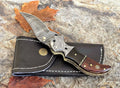 Damascus steel pocket knife with buffalo horn and rose handle, crafted by SHAM KNIVES, featuring a detailed blade and elegant handle.