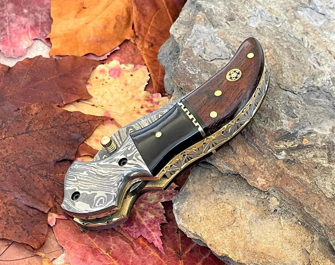 Damascus steel pocket knife with buffalo horn and rose handle by SHAM KNIVES, featuring a detailed blade and elegant handle design.