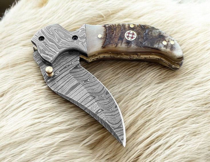 Custom handmade Damascus pocket knife with sheep horn handle, featuring intricate blade pattern and traditional craftsmanship.