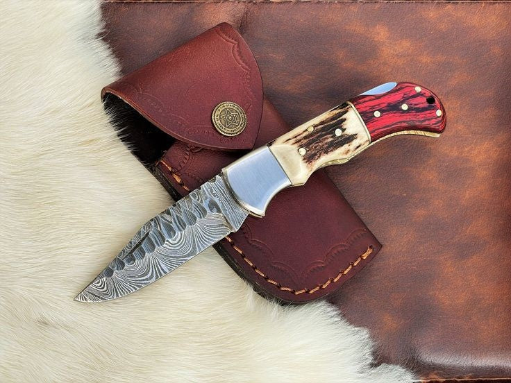 Handmade Damascus pocket knife with stag and pakka wood handle, featuring intricate steel pattern and a sharp blade.