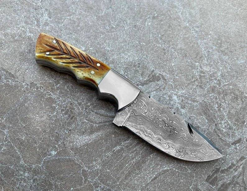 Handmade Damascus steel hunting knife with a carved burnt camel bone handle and fixed blade design by SHAM KNIVES.
