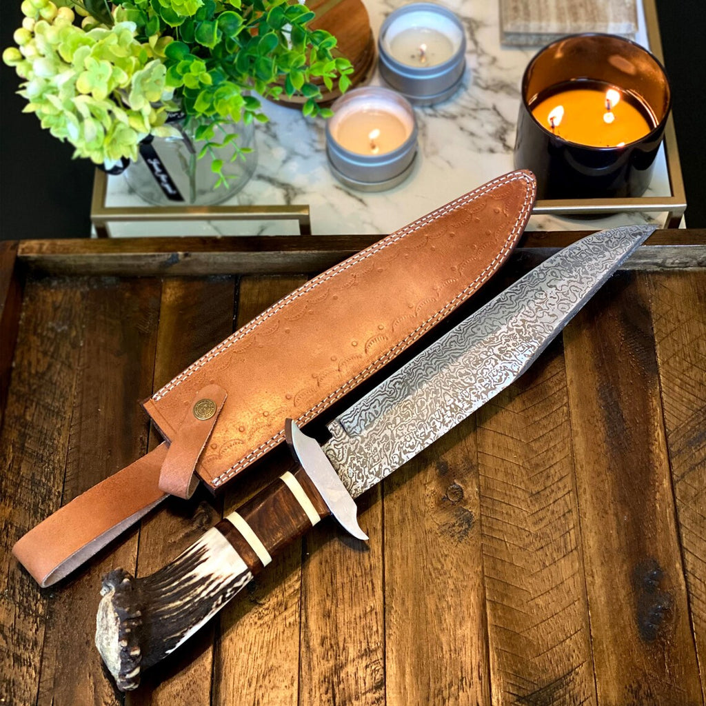 Custom handmade Damascus steel Bowie knife with stag crown handle, rosewood guard, and leather sheath by Knives Gear Garage.