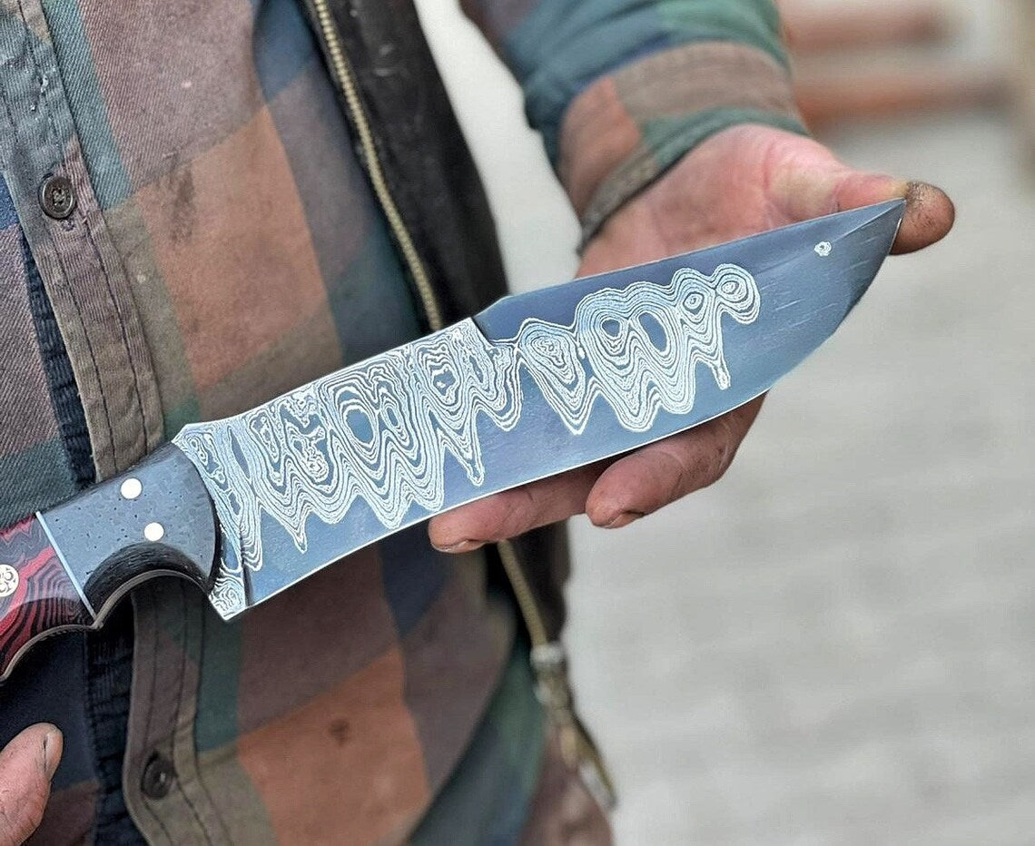 Handmade Damascus steel hunting knife with resin handle and leather sheath, crafted by Knives Gear Garage.