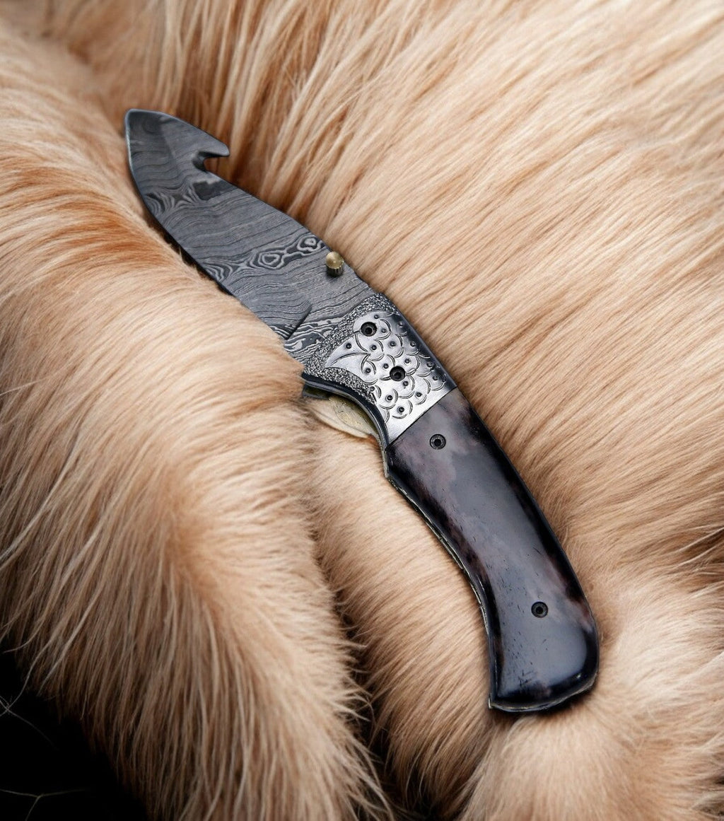 Custom handmade Damascus pocket knife with a colorful bone handle and intricate blade design.
