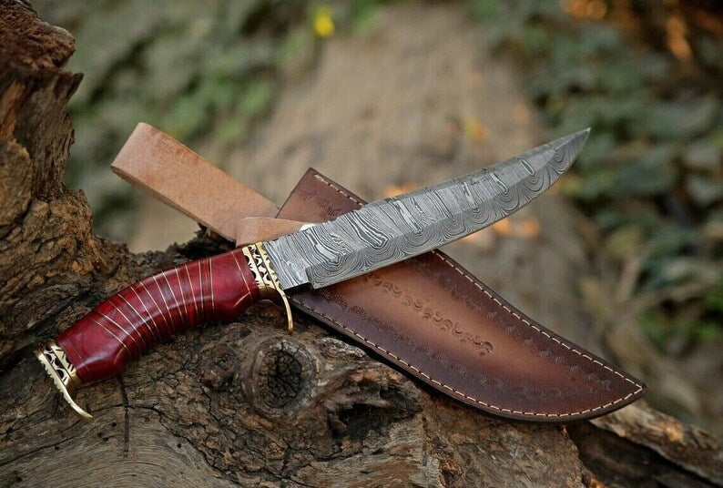 Custom handmade Damascus steel hunting Bowie knife with brass guard and pakkawood handle, shown with leather sheath.