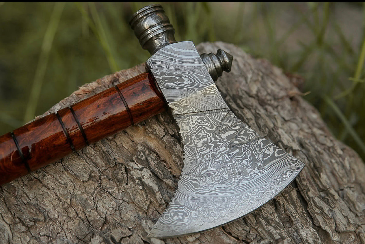 Damascus hunting axe with rosewood handle and leather sheath, crafted by Knives Gear Garage, displayed with detailed blade and handle.