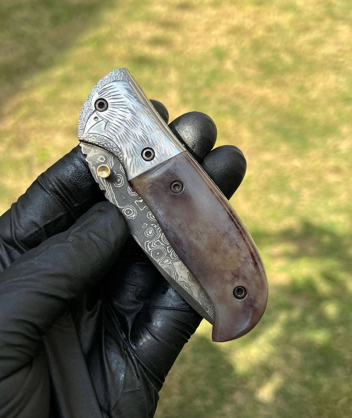 Damascus pocket folding knife by cskforged with a patterned blade, stainless steel handle, and a secure locking mechanism.