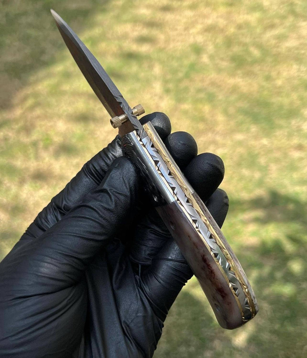 Damascus pocket folding knife by cskforged with a patterned blade and sturdy handle, displayed in a folded position.