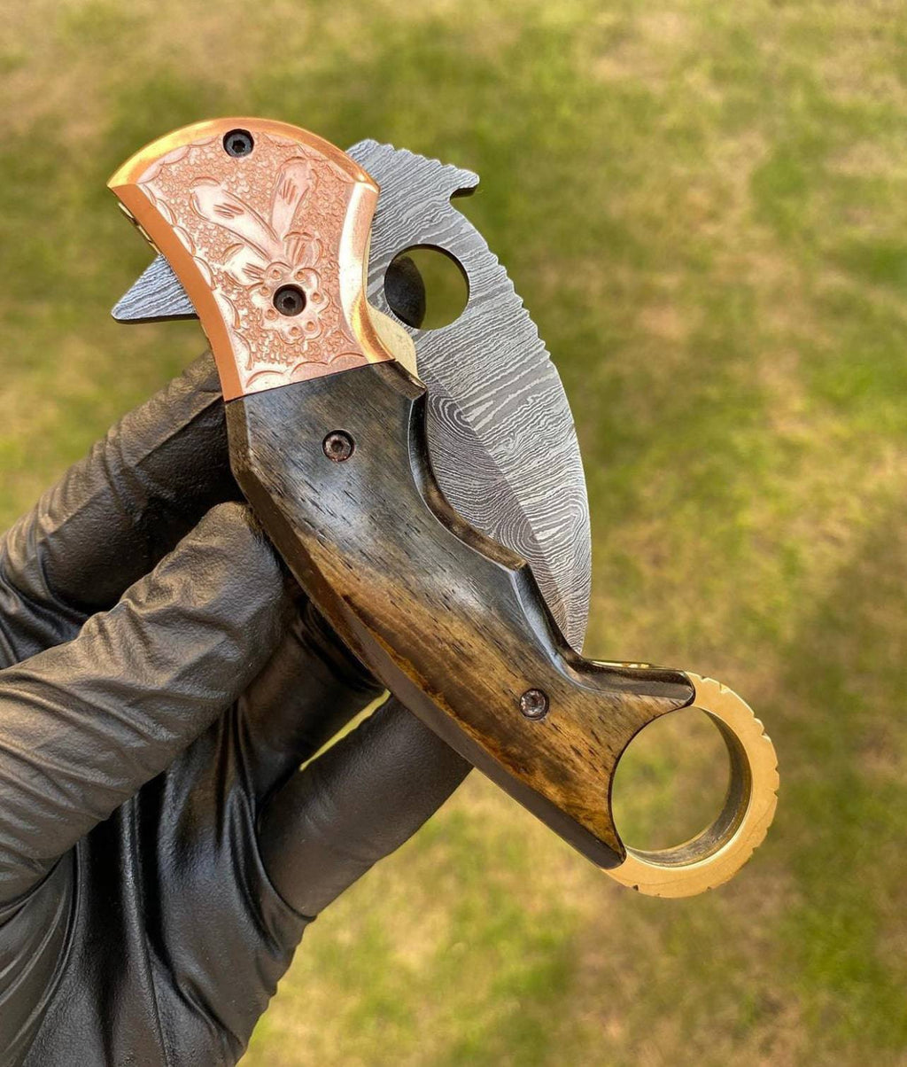 Damascus folding pocket knife with karambit design by cskforged, featuring intricate blade patterns and ergonomic handle.