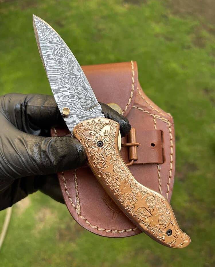 Custom handmade Damascus blade EDC folding pocket knife by CSK Forged with a detailed pattern on the blade and a textured handle.
