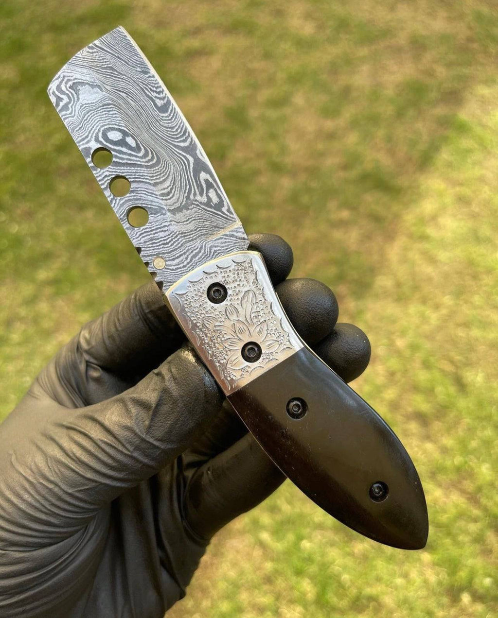Damascus pocket folding knife by cskforged featuring a patterned steel blade and a sleek black handle.