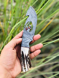 Handmade Damascus steel Guthook skinning knife with custom handle by Knives Gear Garage, showing its sharp blade and detailed craftsmanship.