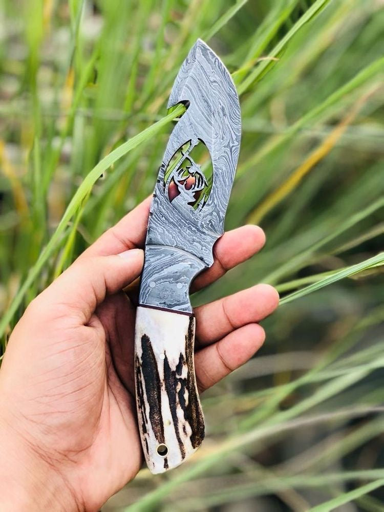 Handmade Damascus steel Guthook skinning knife with custom handle by Knives Gear Garage, showing its sharp blade and detailed craftsmanship.