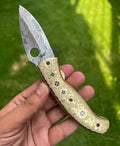 Damascus steel folding pocket knife by cskforged with engraved brass handle, 8-inch custom knife displayed open showing blade details.
