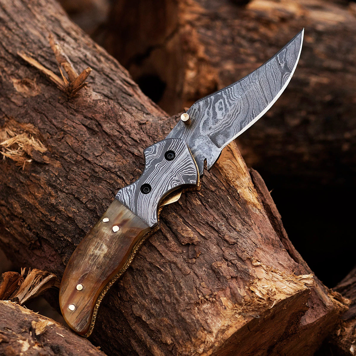 Damascus steel folding knife from Knives Gear Garage with a textured handle and sharp blade, displayed on a wooden surface.