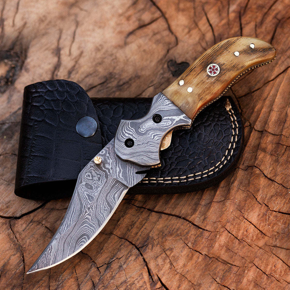Damascus steel folding knife with intricate pattern, black handle, and partially open blade from Knives Gear Garage.