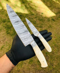 Custom handmade Damascus steel chef knives set by cskforged, featuring two high-quality, intricately patterned blades on a wooden surface.