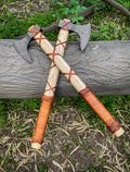 Pair of Damascus Viking axes with ashwood handles, leather wraps, and sheaths, featuring intricate blade patterns and sturdy craftsmanship.
