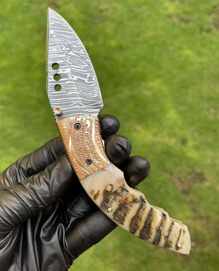 Damascus folding pocket knife by cskforged with a textured blade and ergonomic handle, ideal for everyday carry and outdoor use.
