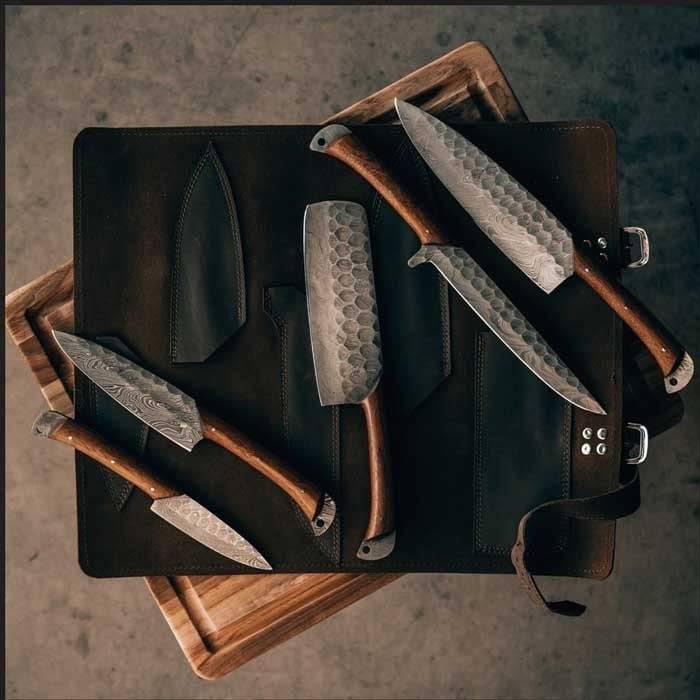 Custom handmade Damascus kitchen knives set with rosewood handles displayed in leather roll kit by Knives Gear Garage.