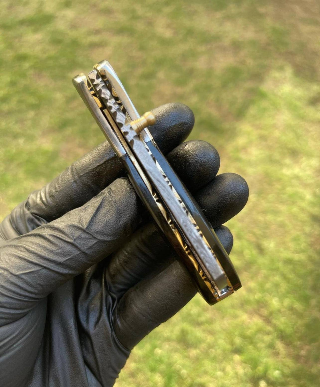 Damascus pocket folding knife by CSK Forged showing a patterned Damascus steel blade and black handle, folded in a close-up view.