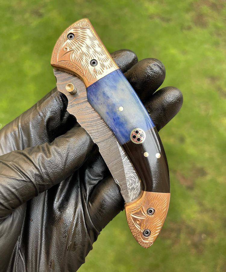 Damascus Blade EDC folding pocket knife by cskforged with a textured Damascus steel handle and a sharp folding blade.