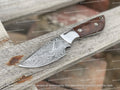 Custom handmade Damascus steel skinning knife with a textured handle and sharp blade, ideal for outdoor hunting and skinning tasks.