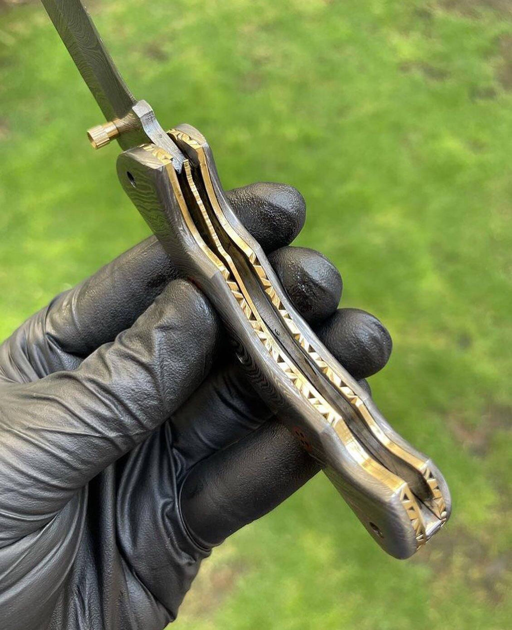 Damascus folding pocket knife with a full blade and textured handle by cskforged, shown partially open in a close-up view.