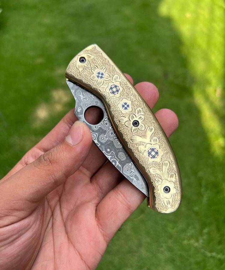 Damascus steel folding pocket knife with engraved brass handle by CSK Forged, 8-inch custom knife, open blade with intricate details.