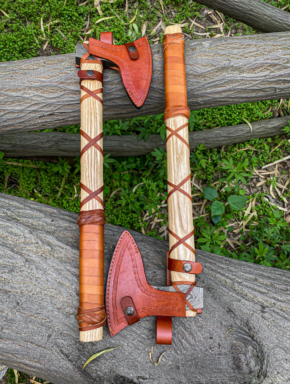 Damascus Viking axe pair with ashwood handles, leather wraps, and sheaths, crafted by Knives Gear Garage.