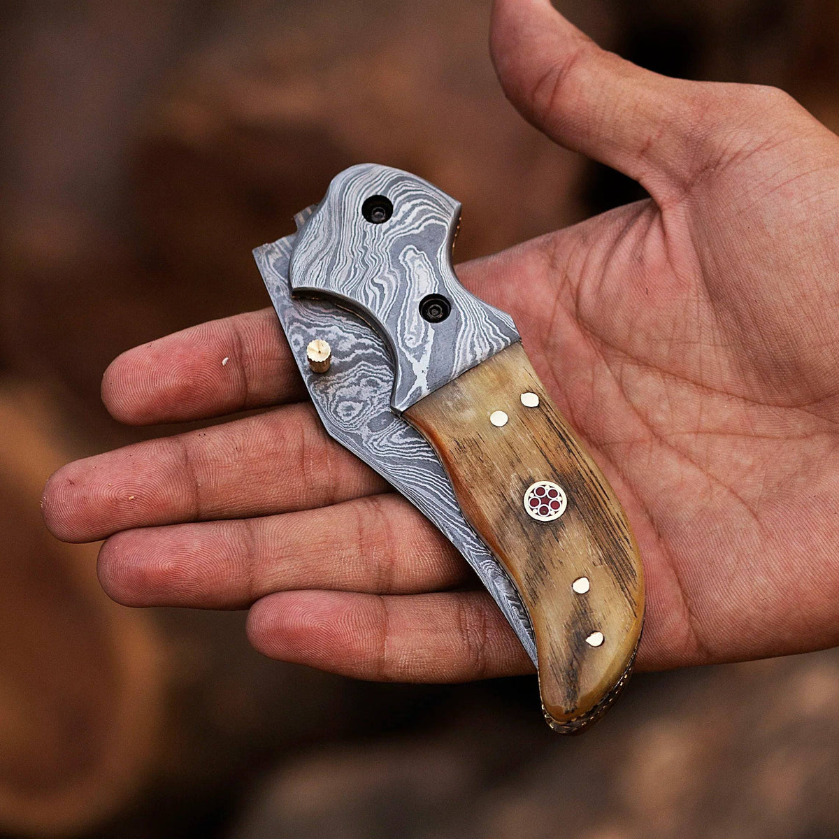 Damascus steel folding knife with intricate pattern, stainless steel blade, and ergonomic handle from Knives Gear Garage.