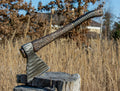 Hand-forged Viking axe from Knives Gear Garage with wooden handle and sharp steel blade, displayed on a rustic background.