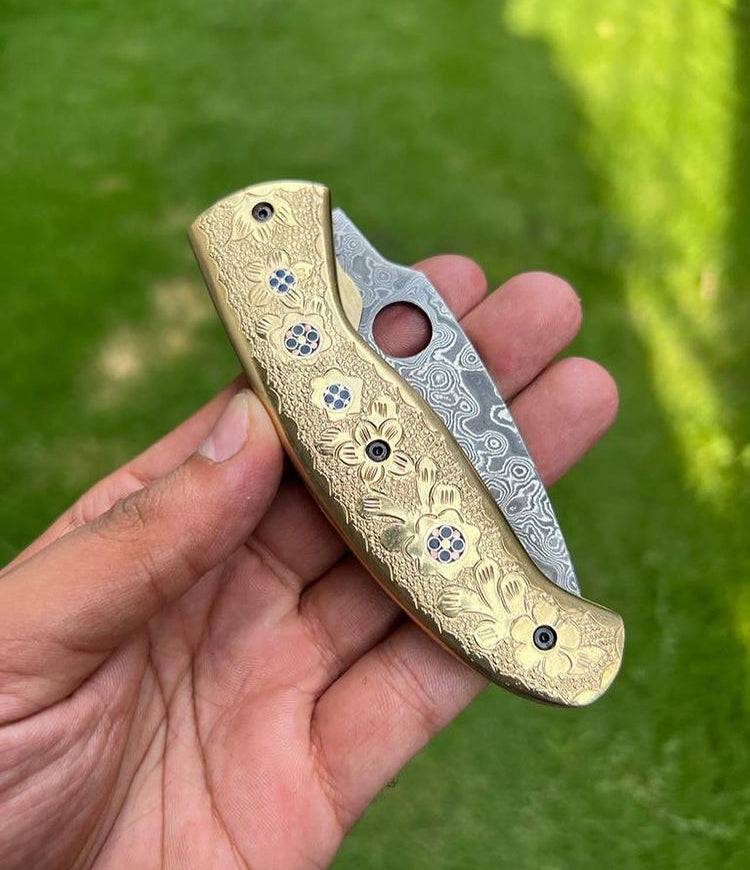 Damascus steel folding pocket knife with engraved brass handle from CSK Forged, featuring an 8-inch blade and intricate design.