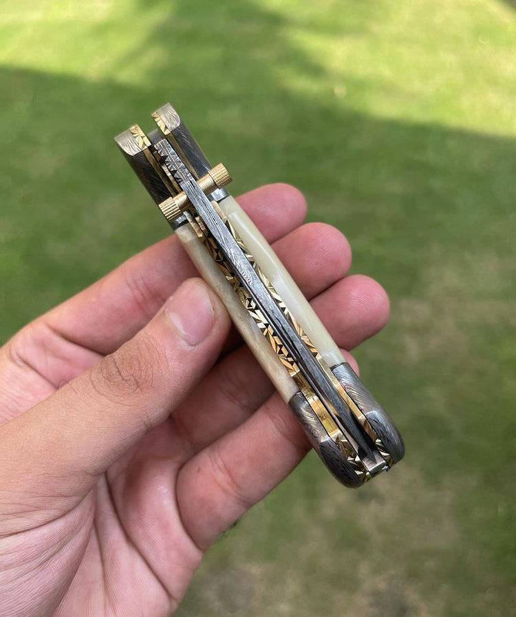 Damascus folding pocket knife by cskforged with a sleek blade and textured handle, shown partially folded on a neutral background.