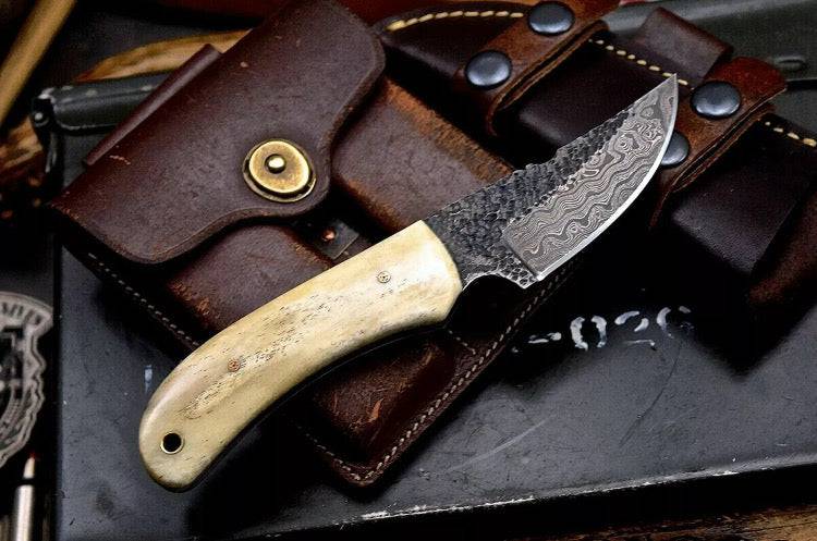 Handmade 7-inch Damascus steel deer skinning knife with camel bone handle and leather sheath, ideal for hunting and skinning tasks.