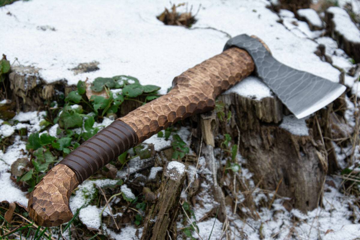 Hand-forged axe from Knives Gear Garage featuring a wooden handle and sharp metal blade for outdoor chopping tasks.