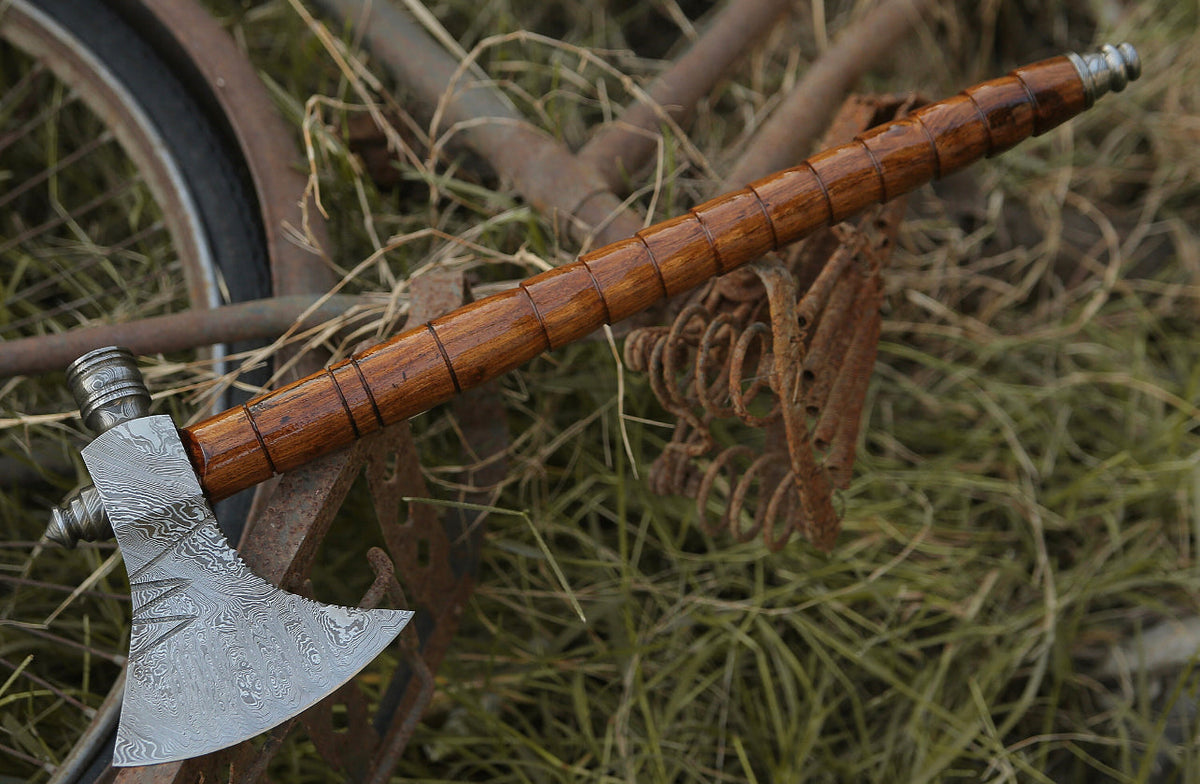 Damascus hunting axe with rosewood handle and leather sheath, crafted by Knives Gear Garage, shown with detailed blade and handle.